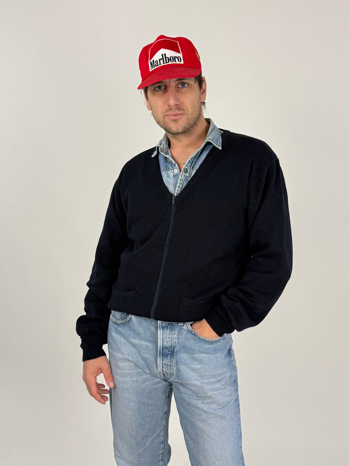 Giacca maglia Vancini - retro indossato, blu notte uniforme, cappellino rosso Marlboro, jeans chiari, silhouette bomber corta