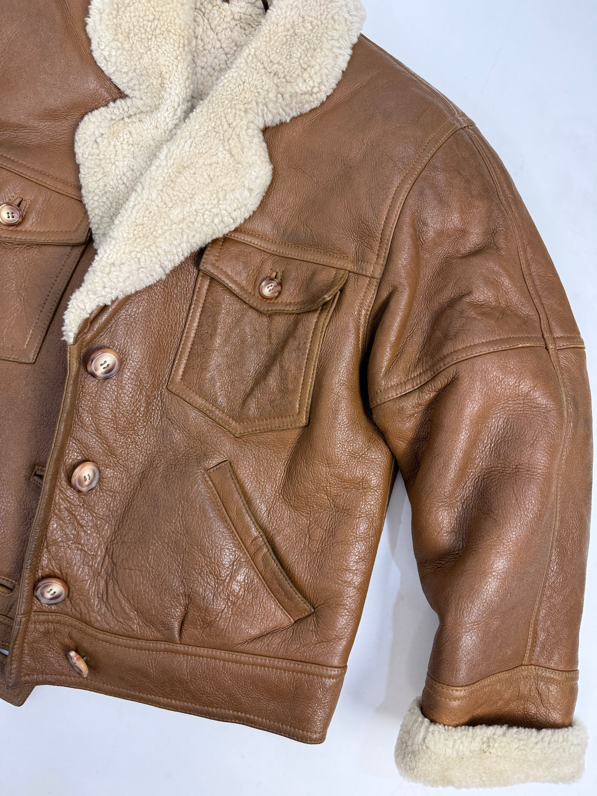 Giacca montone vintage - fronte indossato chiuso tre quarti, cinque bottoni resina avorio, tasche petto patta rettangolare, orlo banded cuoio, polsini shearling crema