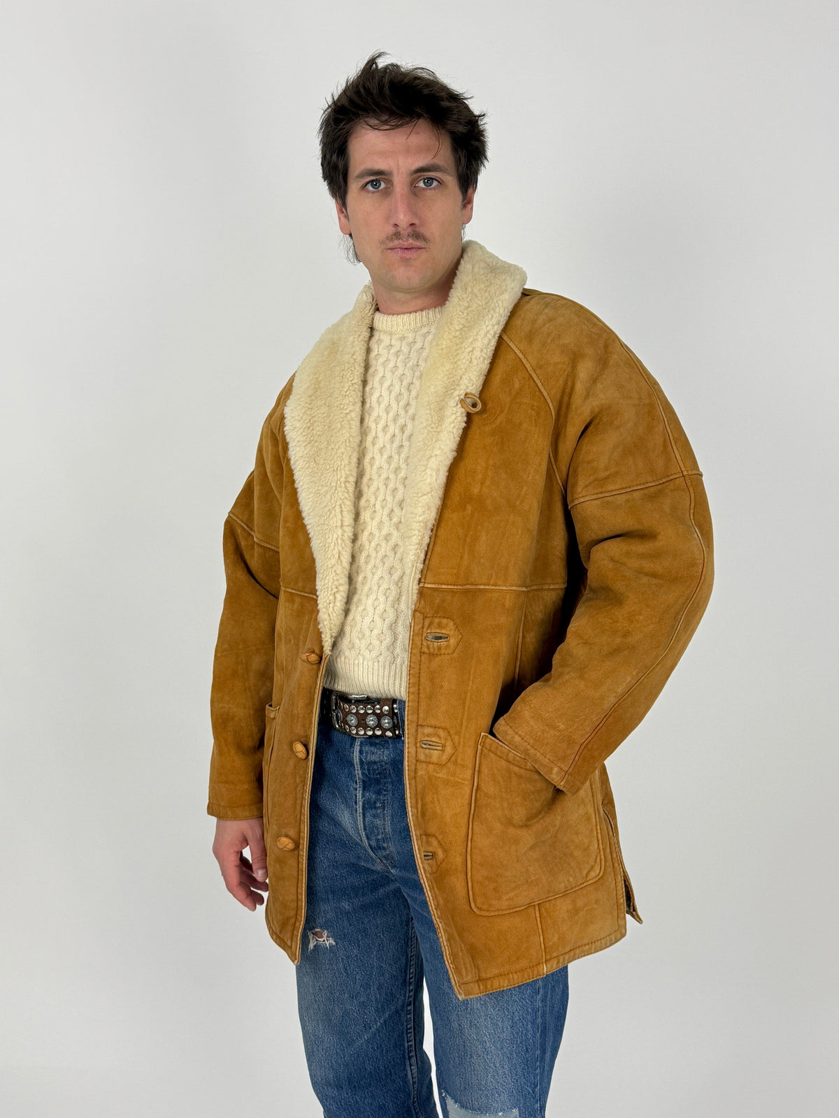 Swearling ranch coat - tre quarti indossato laterale, suede tabacco senape opaco, shearling pelo lungo riccio colletto, silhouette oversize boxy, spalle cadenti cm 50, mano in tasca