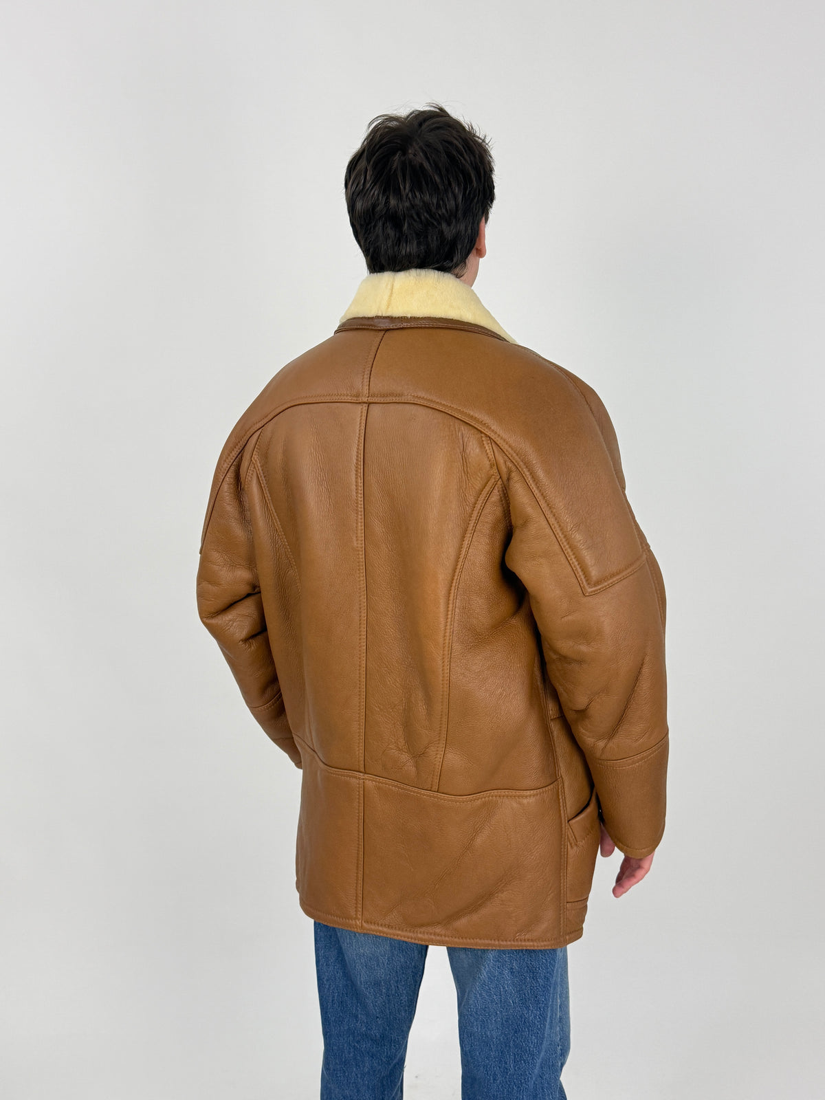 Dettaglio etichetta interna - etichetta SHEARLING ORIGINAL QUALITY bordo ornamentale serif bianca, seconda etichetta oro su fondo marrone, shearling rasato bianco avorio denso, bottone resina cognac