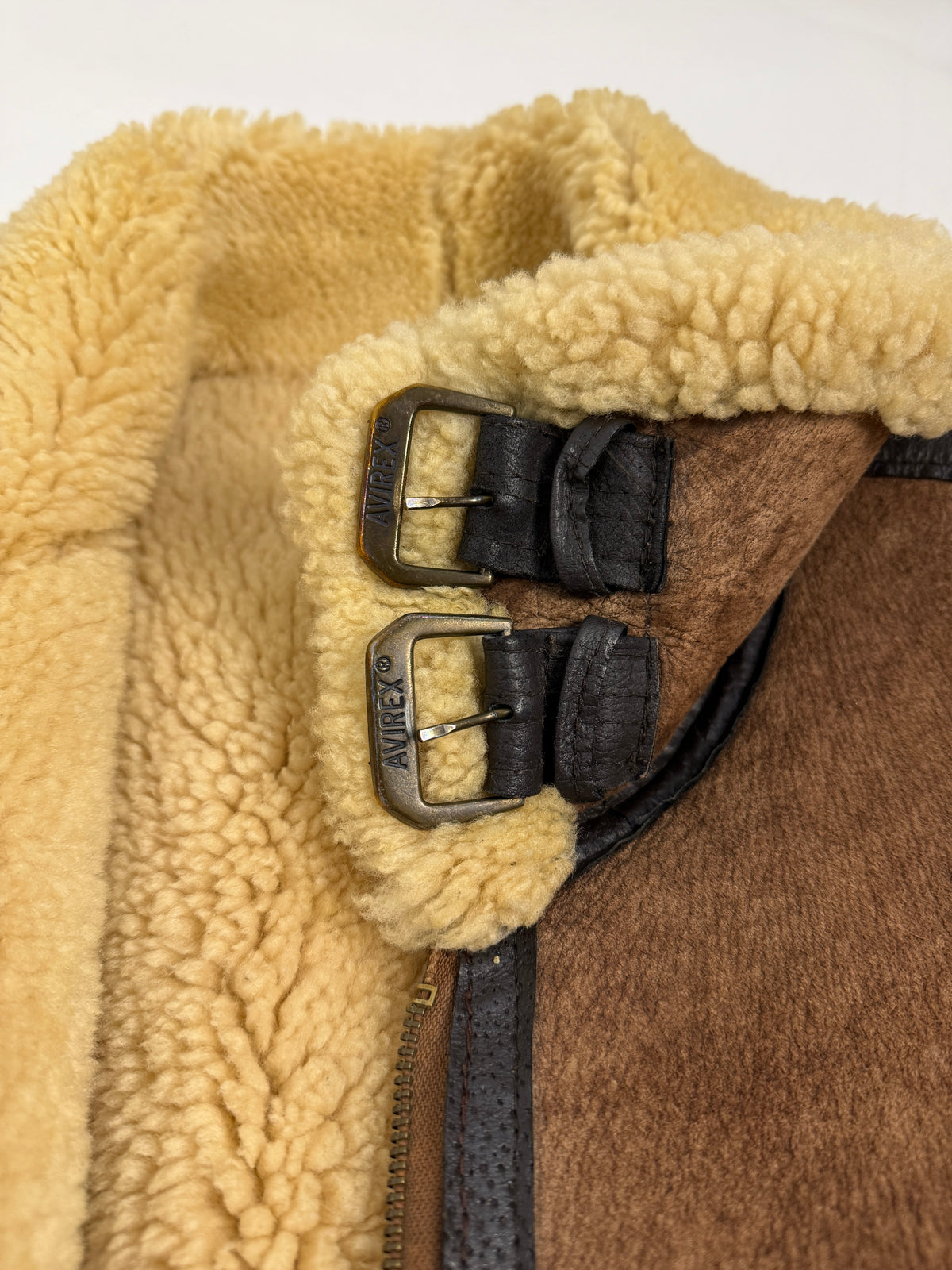 Dettaglio macro fibbie colletto AVIREX - due fibbie rettangolari ottone anticato con incisione AVIREX registrato su cinturini pelle nera, shearling riccio avorio burro colletto B-3