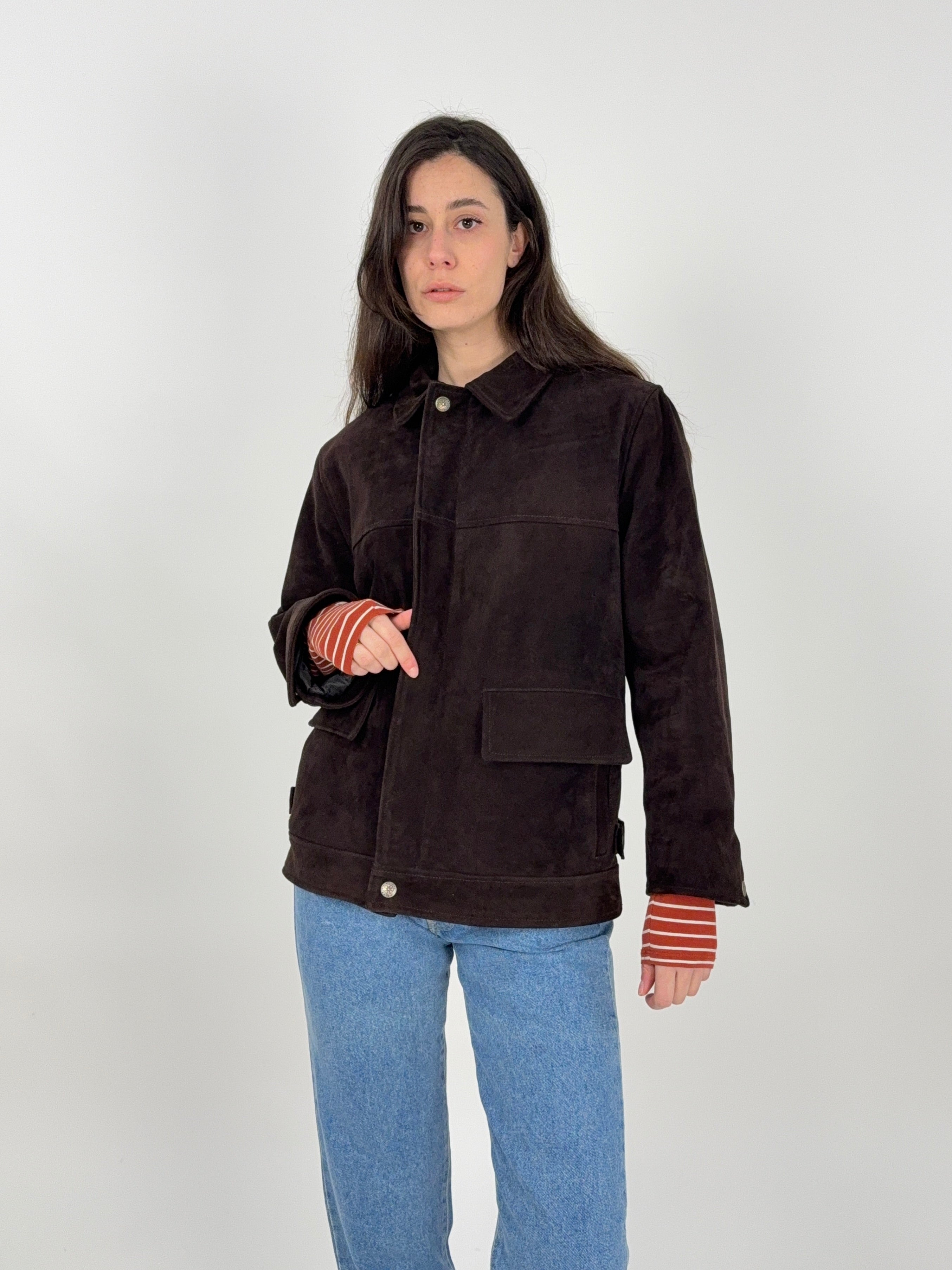 giacca in camoscio marrone indossata su donna, taglio dritto, due tasche a patta. zip di chiusura
