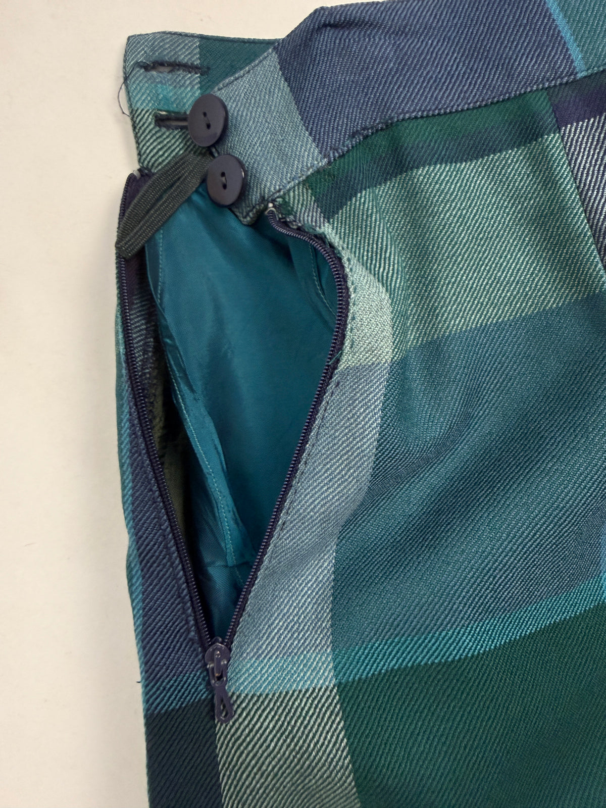 Dettaglio macro zip laterale - zip navy laterale aperta con leggero ristringimento tessuto adiacente dichiarato, bottoni navy fascia vita, fodera interna taffetà teal verde acqua