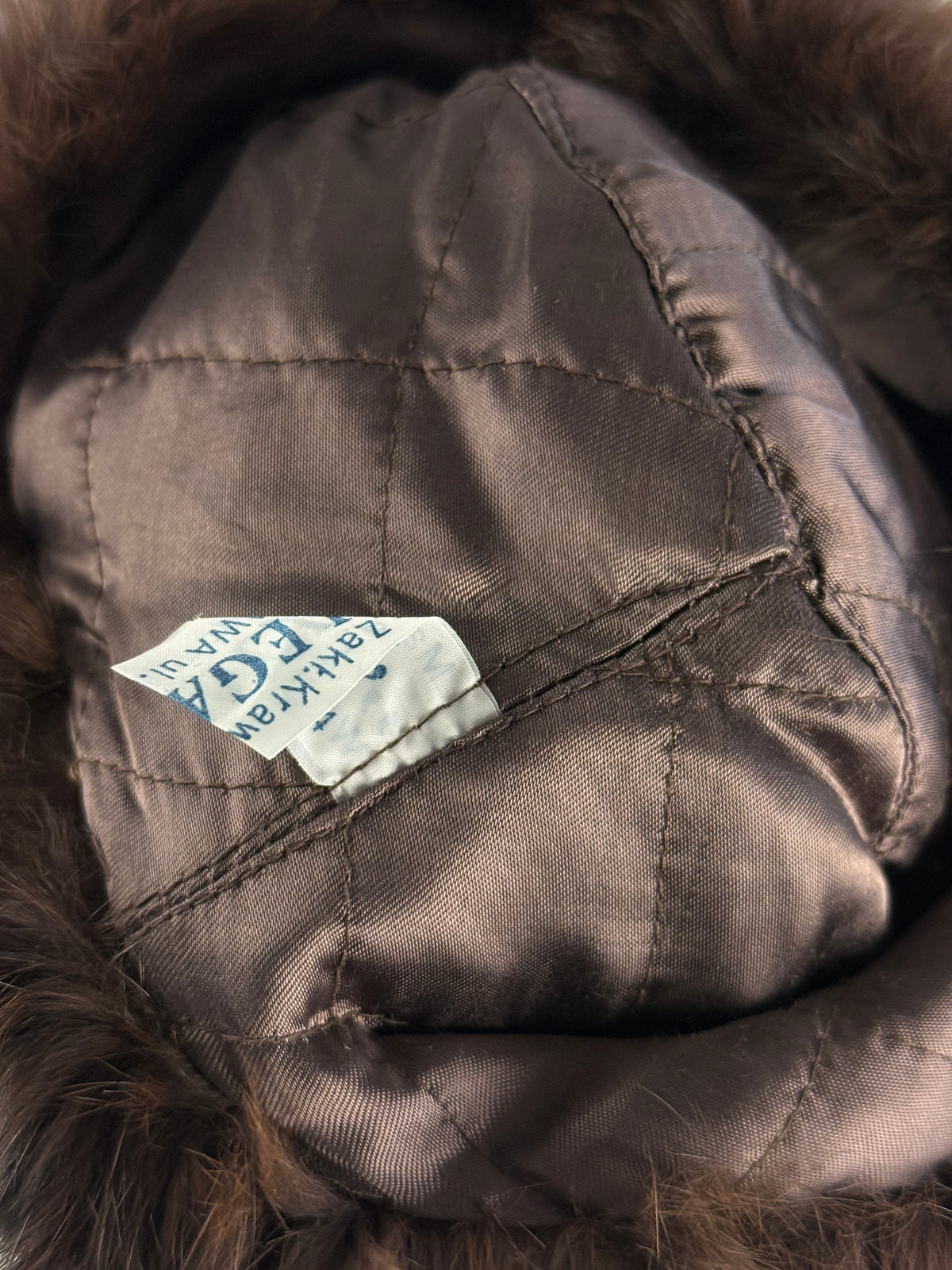 Fodera marrone trapuntata ed etichetta parziale del cappello ushanka