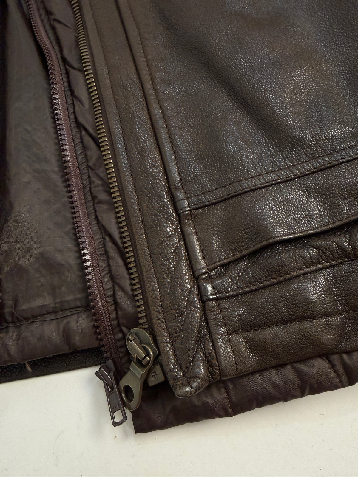 Dettaglio zip doppia frontale - cursori in metallo scuro, pelle marrone con patina naturale e cucitura frontale