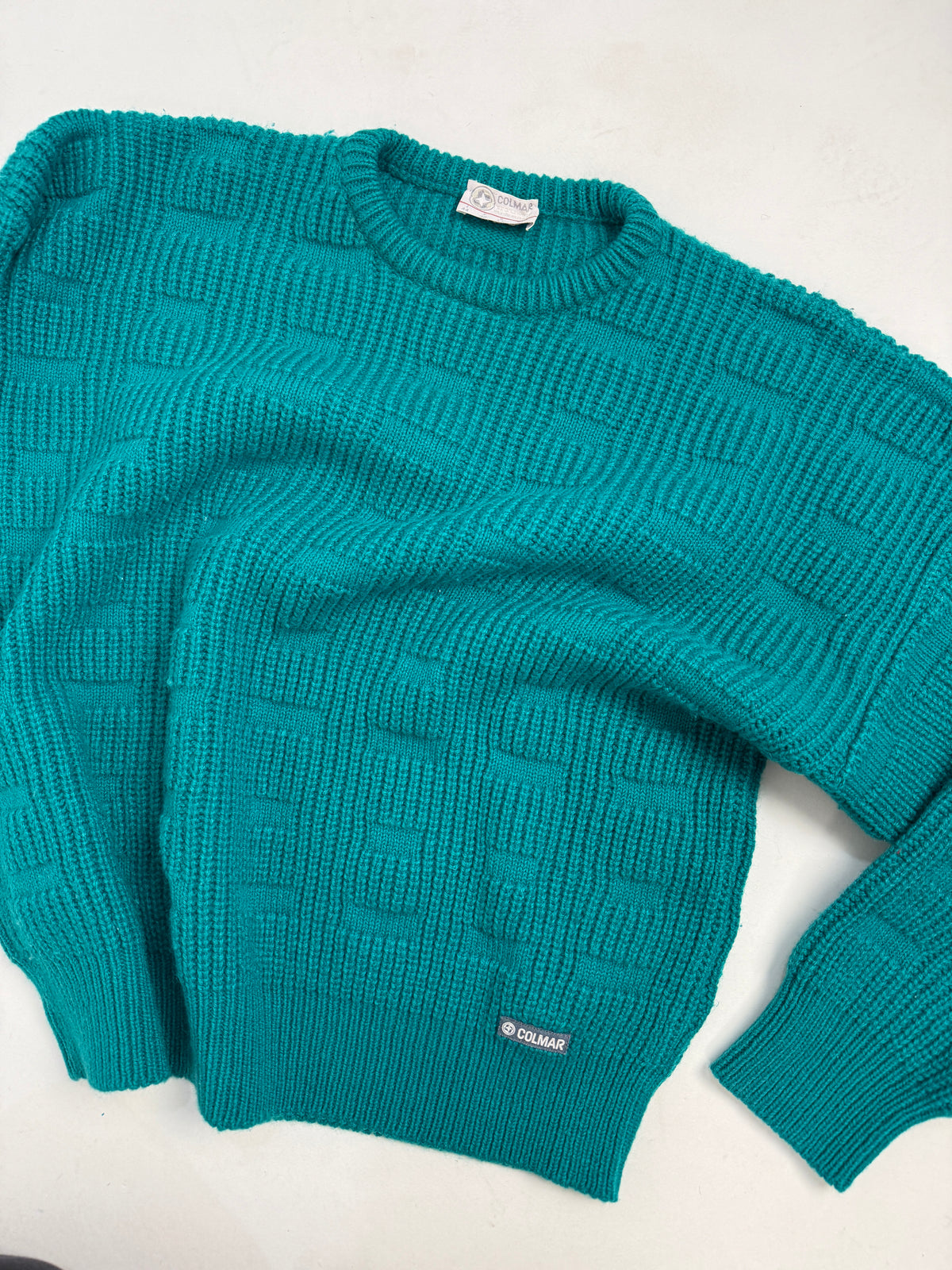 Maglione Colmar piano fronte - verde teal, girocollo costina alta, patch gommato Colmar al fondo sinistro, punto geometrico strutturato