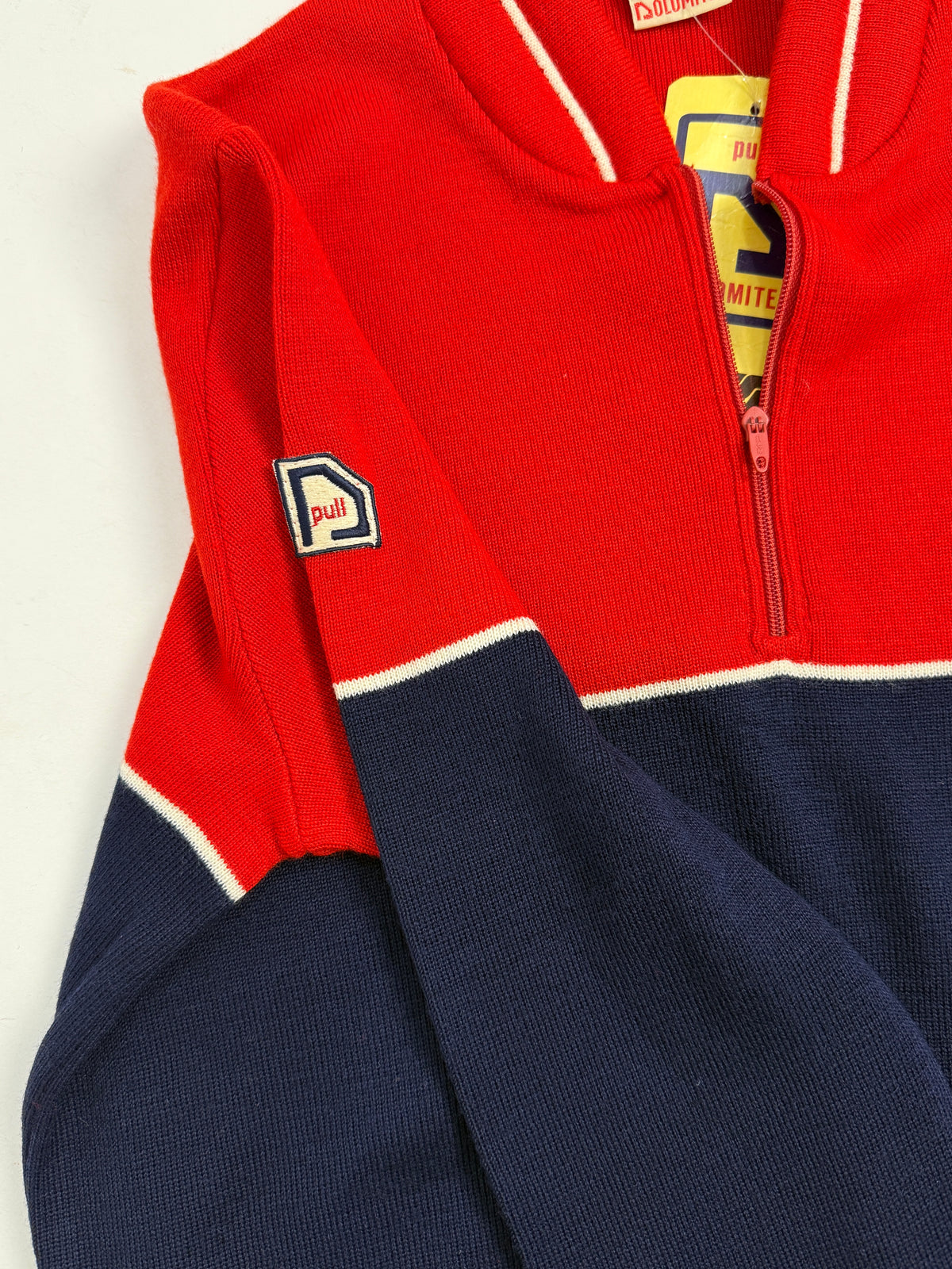 Dettaglio patch ricamato Dolomiten su manicotto - logo pentagono blu/bianco scritta pull in rosso, maglia a punto jersey rosso