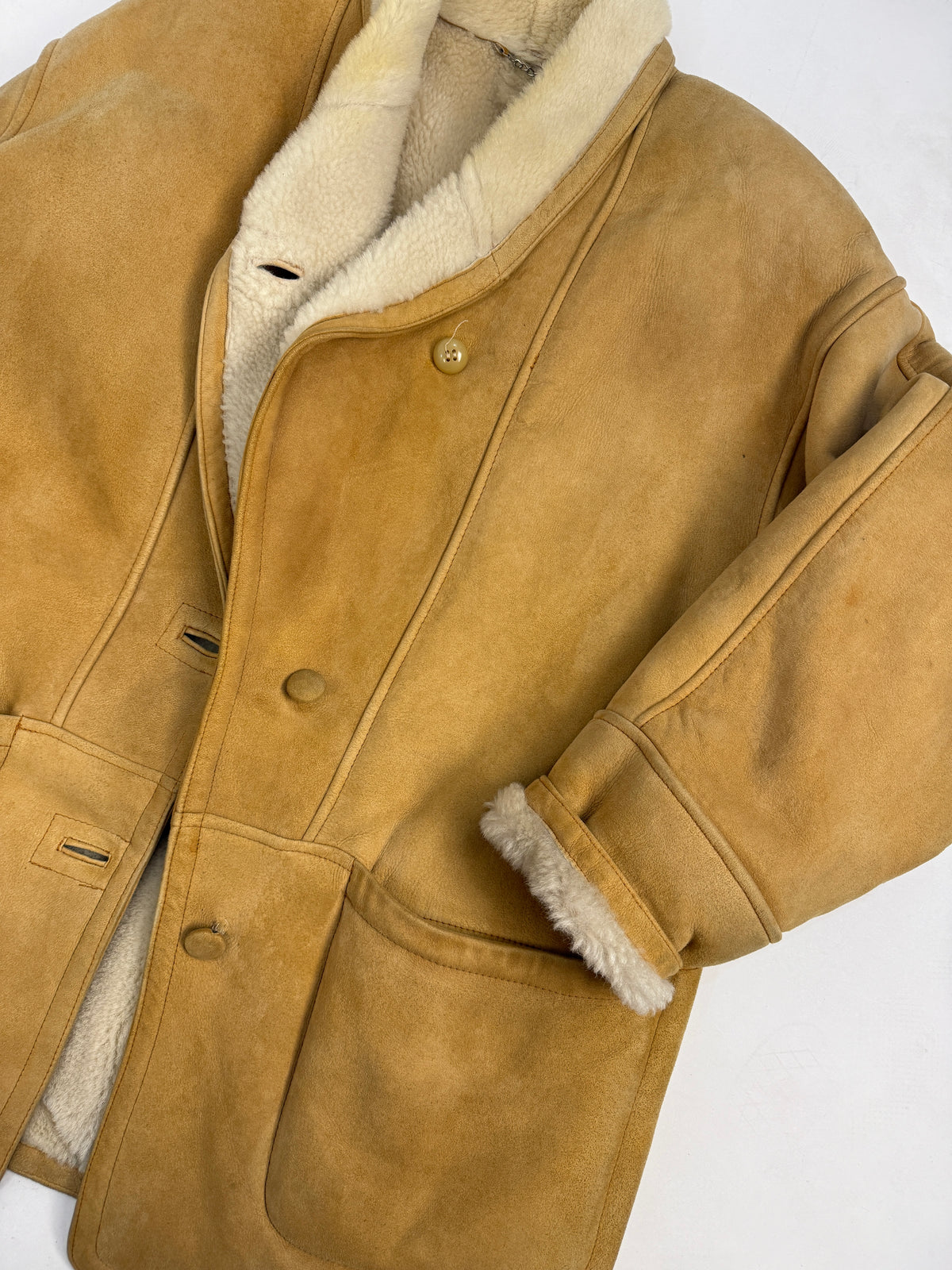 Dettaglio macro colletto e spalla interno - colletto scialle shearling riccio avorio crema abbondante, catena argentata appendiabiti sul bordo interno, suede montone camel grana vellutata