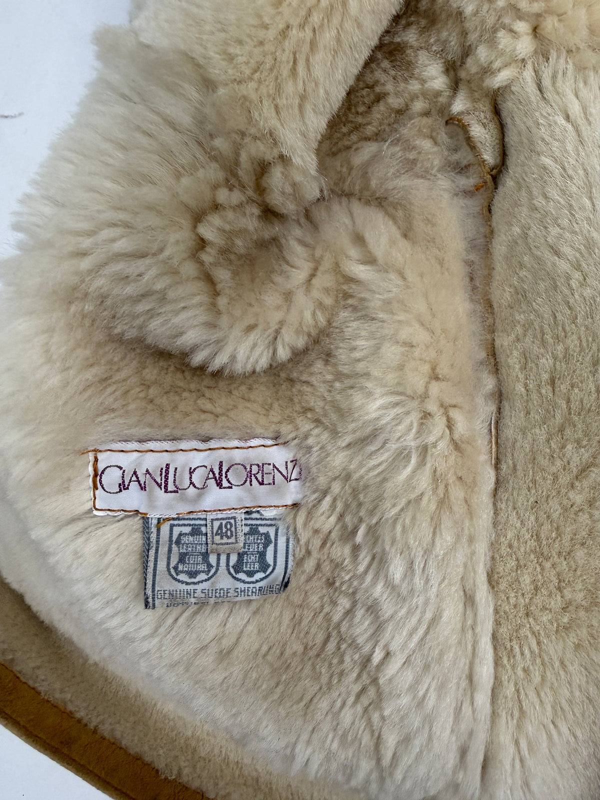 Dettaglio etichetta e tasca interna - etichetta brand Shearling corsivo nero su bianco, tasca interna in shearling riccio avorio crema, suede camel con usura naturale