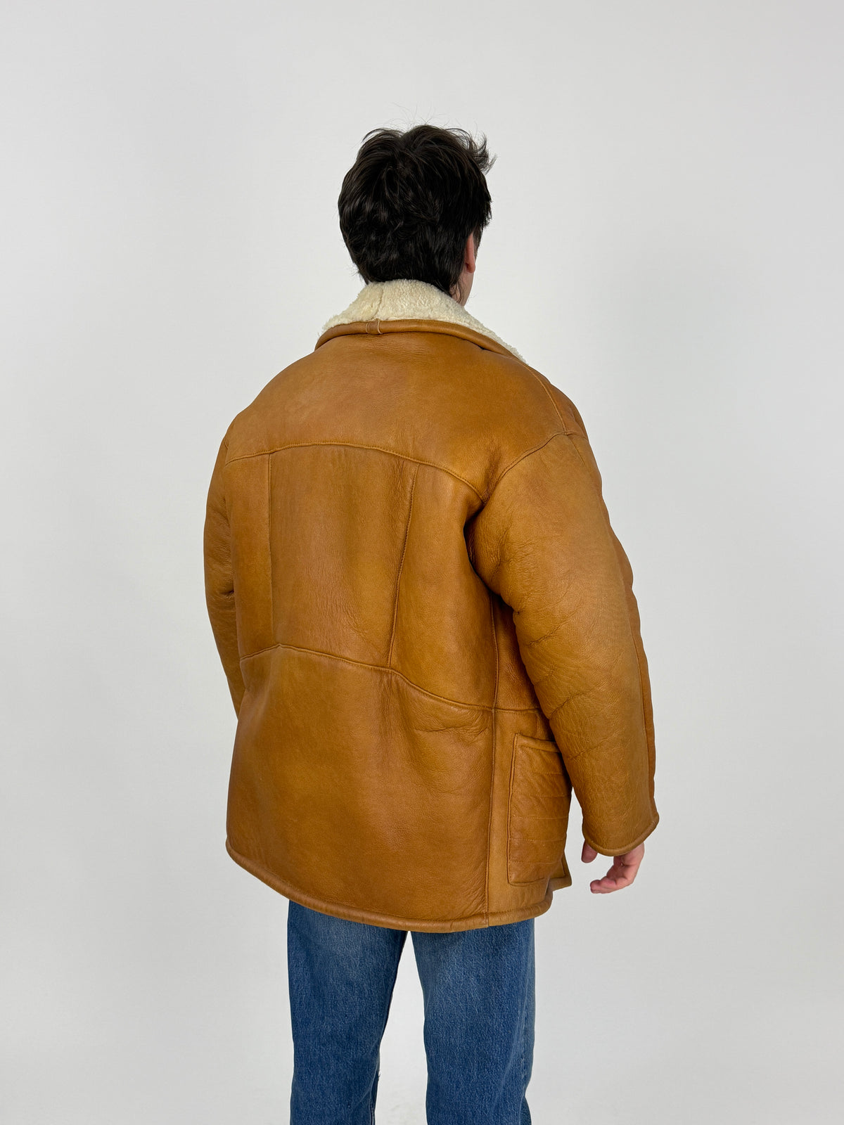 Ranch coat montone - figura intera indossato fronte, nappa caramello cognac, colletto shearling riccio, due toggle legno, tasche basse a soffietto voluminose con passante, lunghezza cm 80