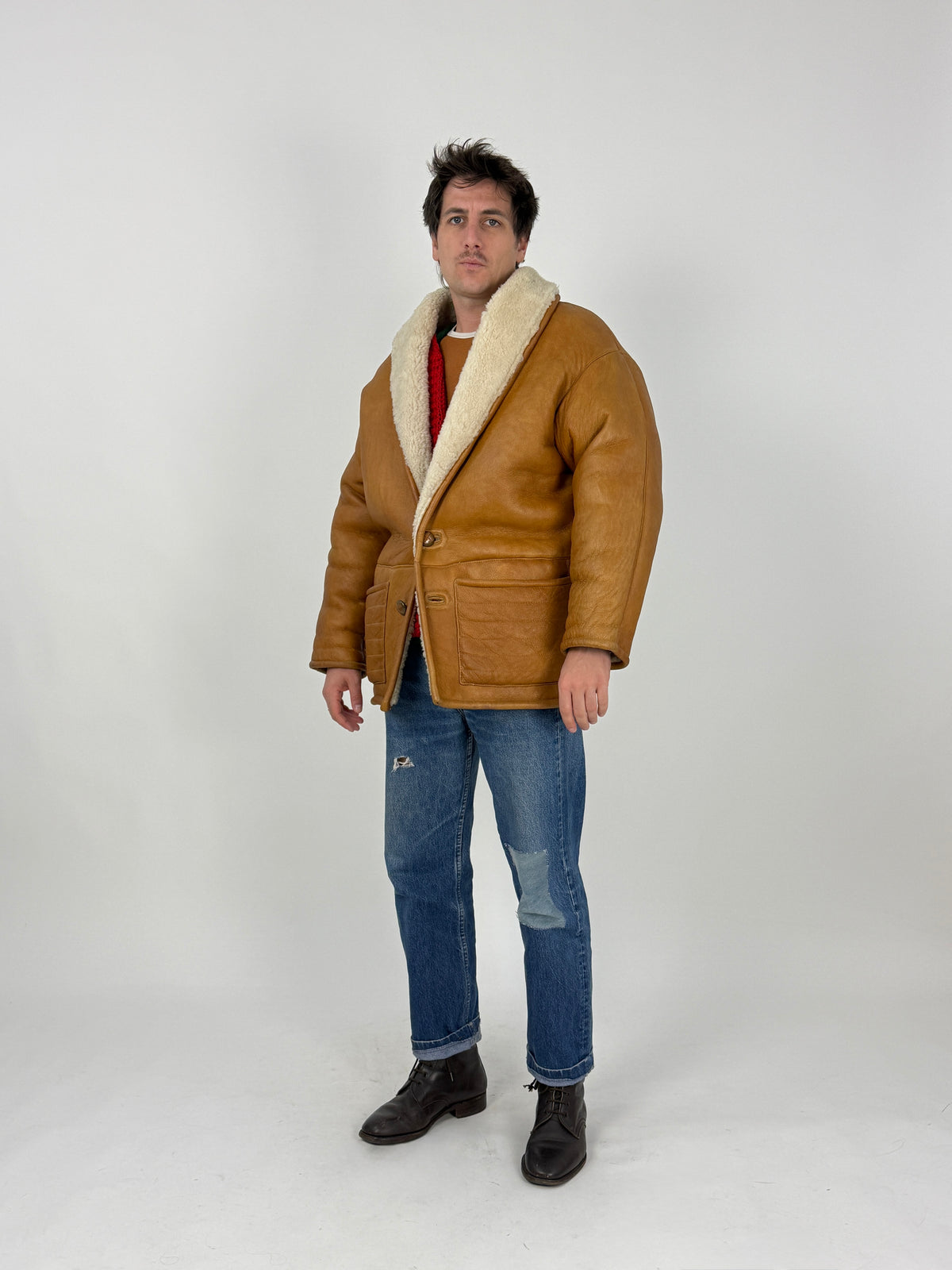 Dettaglio piano fronte - nappa montone cognac grana grossa craquelure pronunciato, due toggle ovale legno naturale su passante cordino, tasche basse soffietto tre sezioni con passante cuoio, colletto shearling riccio