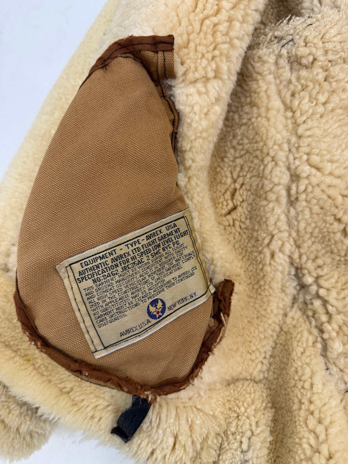Dettaglio macro zip doppio cursore - zip metallo ottone bronzo anticato a denti larghi con doppio cursore, guardia pelle nera goffrata, bordo suede montone marrone, shearling avorio