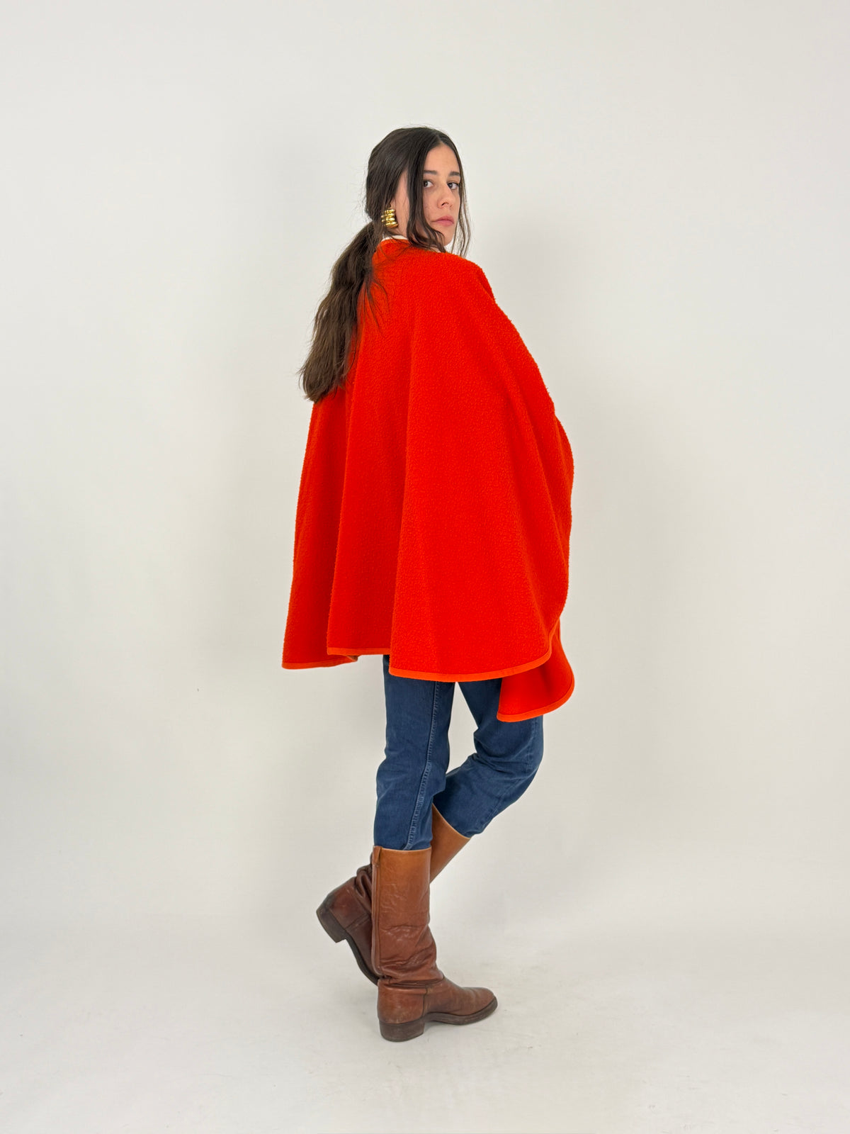 Mantella cape lana bouclé vermiglio - figura intera frontale aperta, braccia aperte aperture laterali, massima ampiezza orizzontale cape circolare, bordi costina coordinata vermiglio