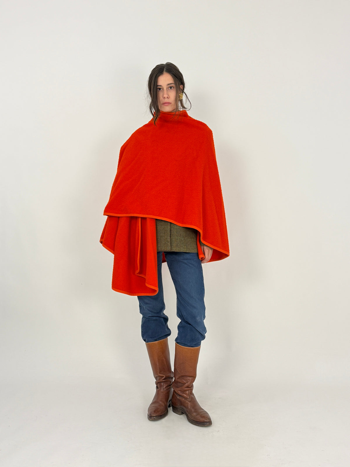 Via Delle Legge mantella cape - frontale tre quarti aperta, bordi frontali aperti costina coordinata, collo dolcevita integrato, lana bouclé vermiglio, stivali cuoio marrone jeans denim