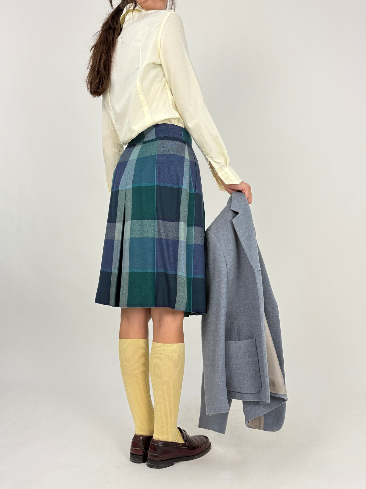 Belfe gonna tartan - figura intera frontale aperta, pieghe piatte box pleats ben visibili, pattern tartan maxi quadri verde navy teal, calzettoni gialli loafers marroni