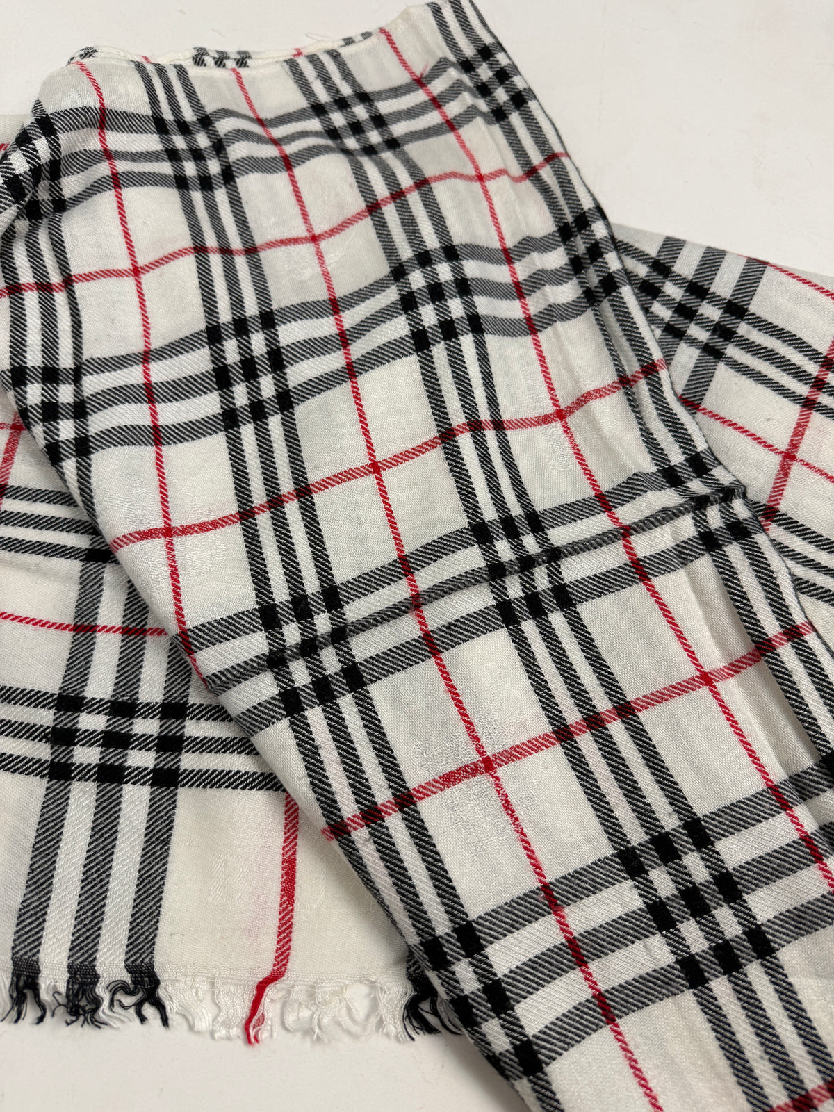 Sciarpa Burberry tartan avorio indossata su un capospalla scuro