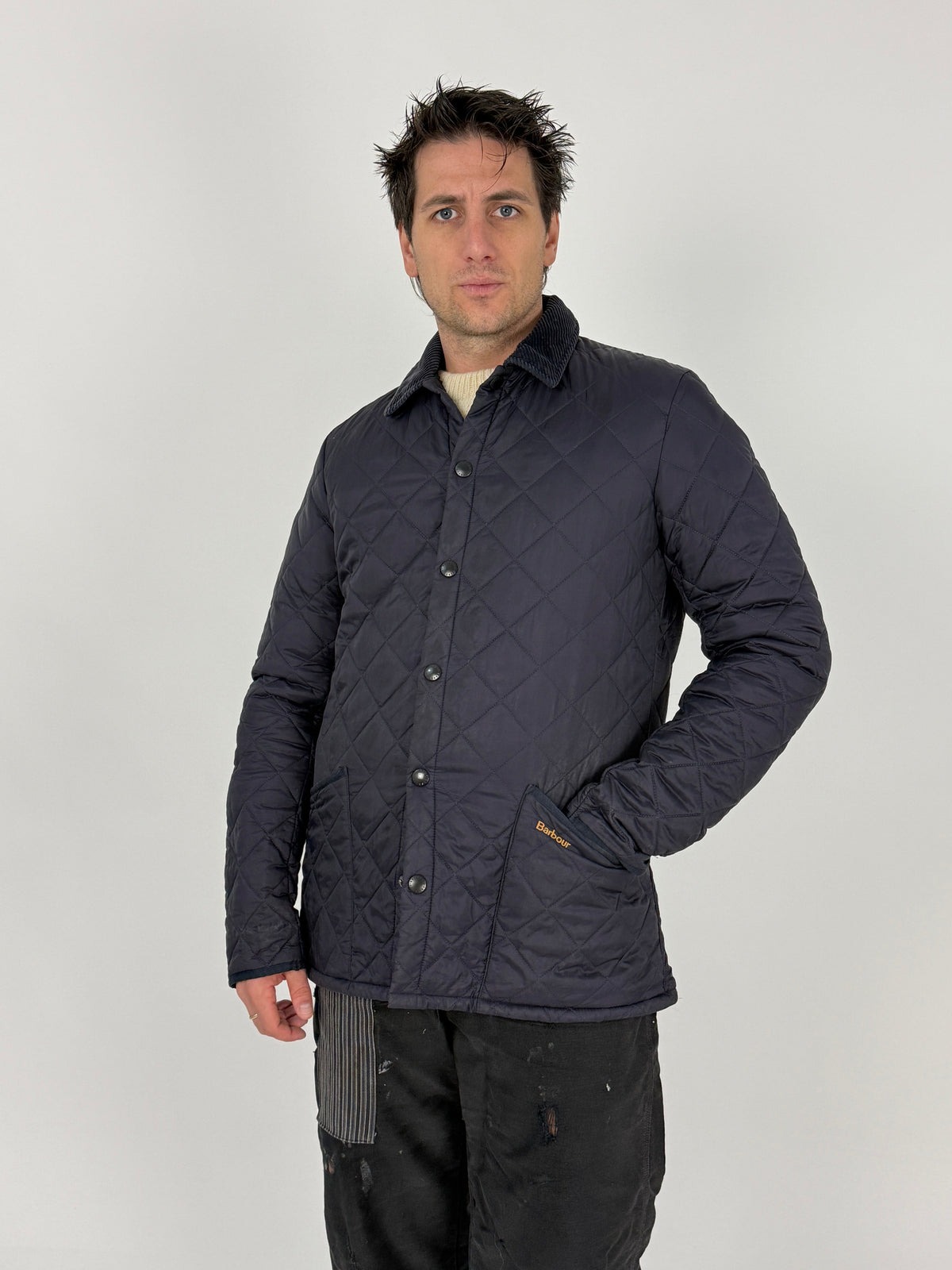 Dettaglio tasca anteriore con logo Barbour ricamato oro e polsino velluto a coste