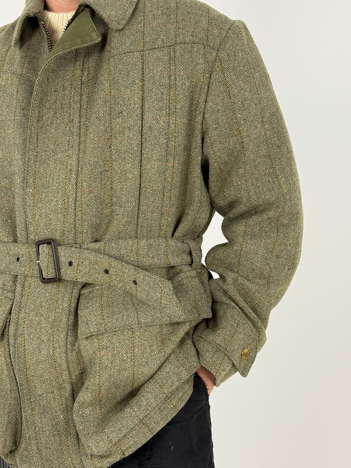 Dettaglio frontale giacca tweed verde oliva - cintura con fibbia, tasche a soffietto e zip con sottoveste canvas