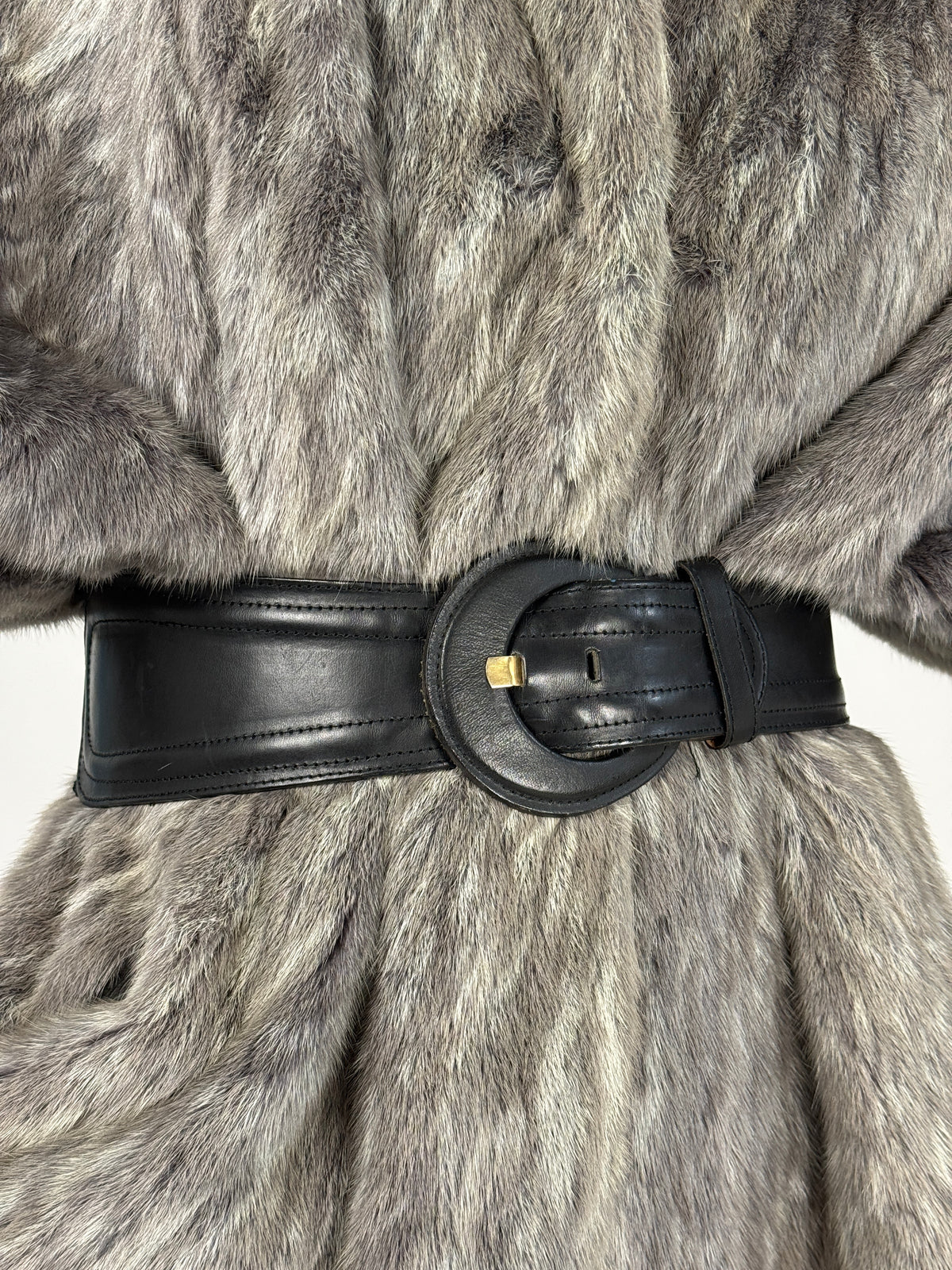 Cintura vintage nera alta con fibbia rotonda indossata su un capospalla